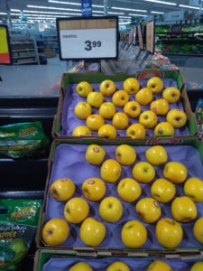 Crates of apples on display beneath a sign for pineapples.