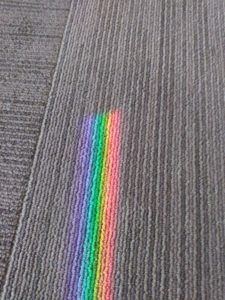 A rainbow stops on a patch of carpet.