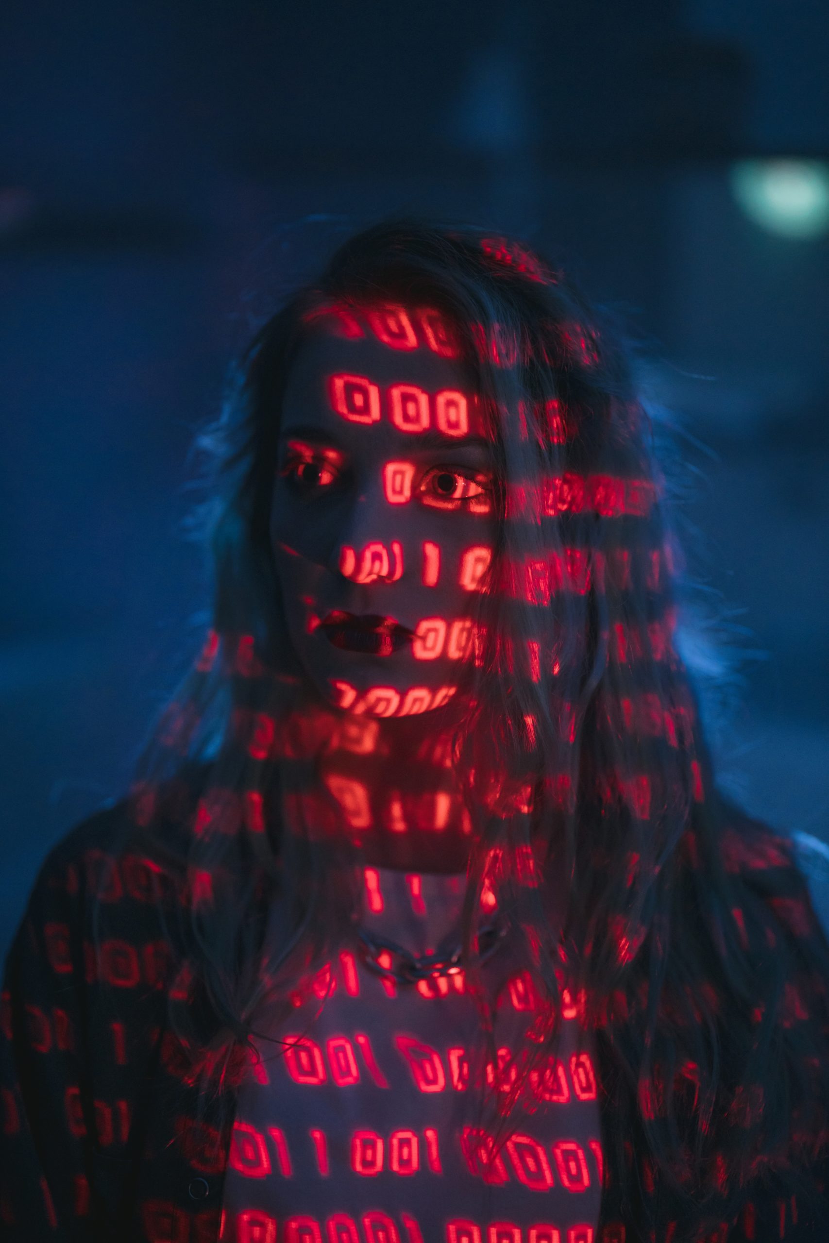 Binary code is projected onto a woman wearing a t-shirt and sweater.