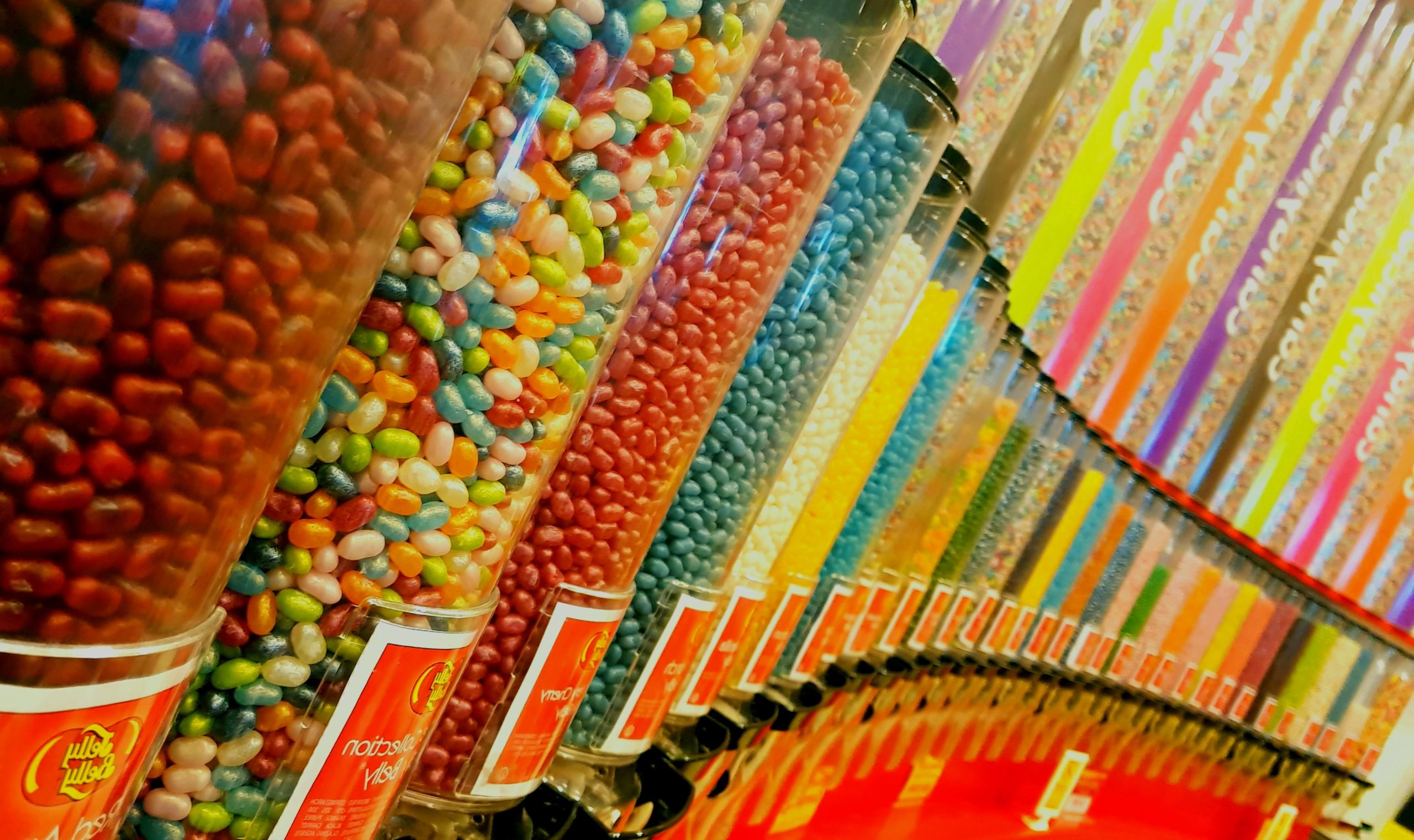A color photo of rows of glass containers filled with colorful jelly beans.